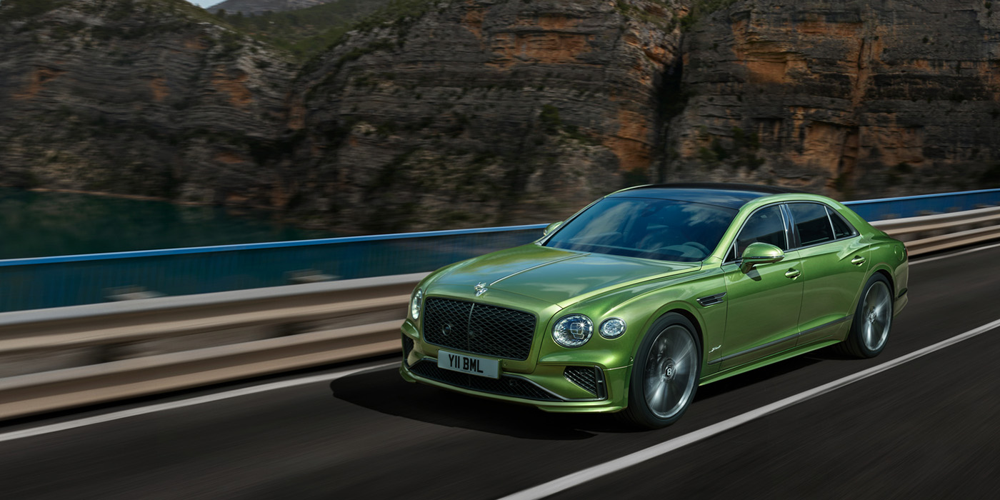 Bentley Riga Bentley New Flying Spur Speed v8 hybrid sedan driving dynamically on a mountain road in Tourmaline Green paint