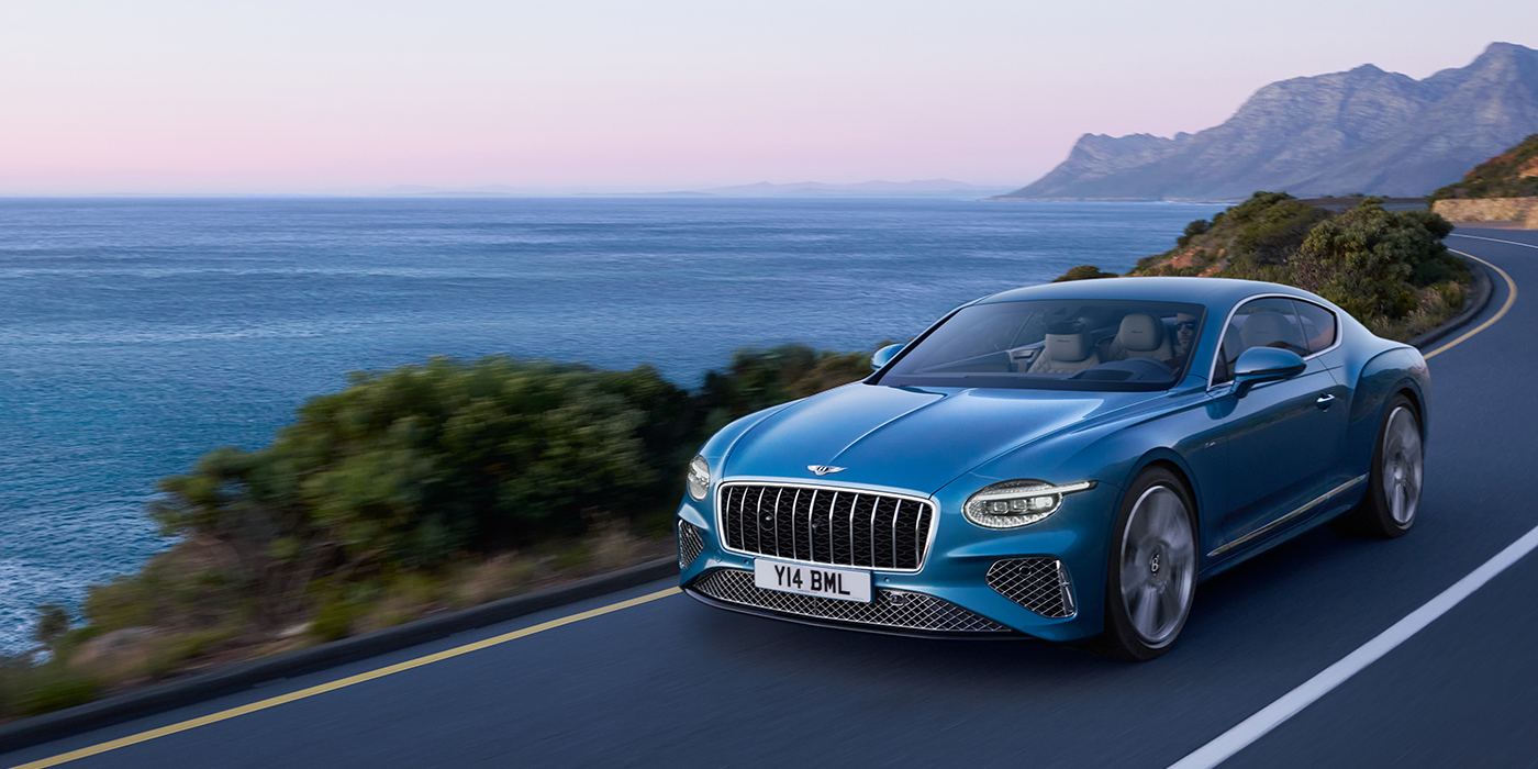 Bentley Riga New Bentley Continental GT Azure coupe in Light Windsor blue paint with 22 inch Azure wheels and chrome grill, driving dynamically by the sea