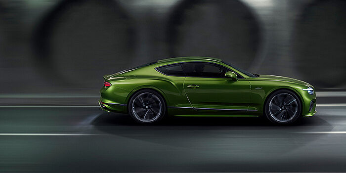  Bentley Riga Bentley Continental GT coupe in Tourmaline Green paint driving in profile on a dark road