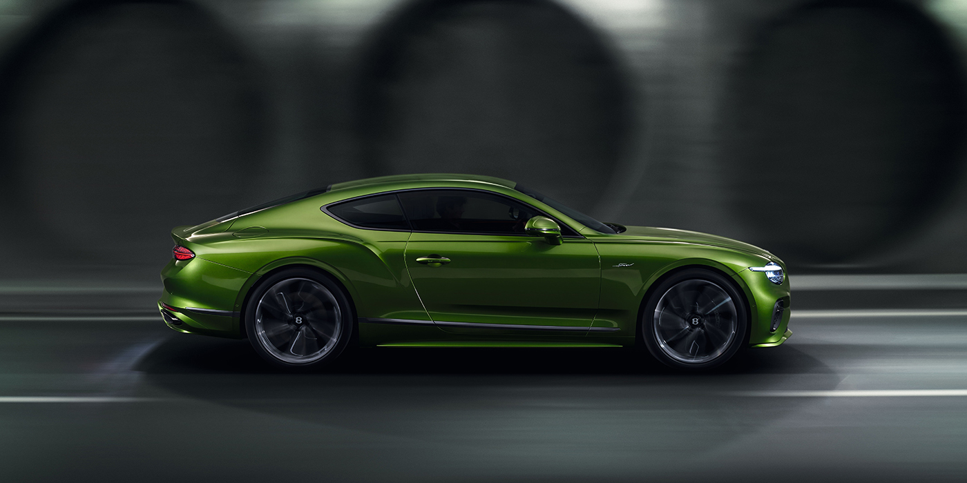 Bentley Riga Bentley Continental GT coupe in Tourmaline Green paint driving in profile on a dark road